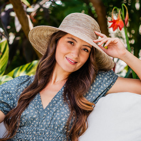 A stunning woman showcases this packable beige beach hat, offering both style and UPF 50+ sun protection. Recommended by the Skin Cancer Foundation, this wide-brimmed hat is both fashionable and functional, perfect for chic sun protection on any adventure.